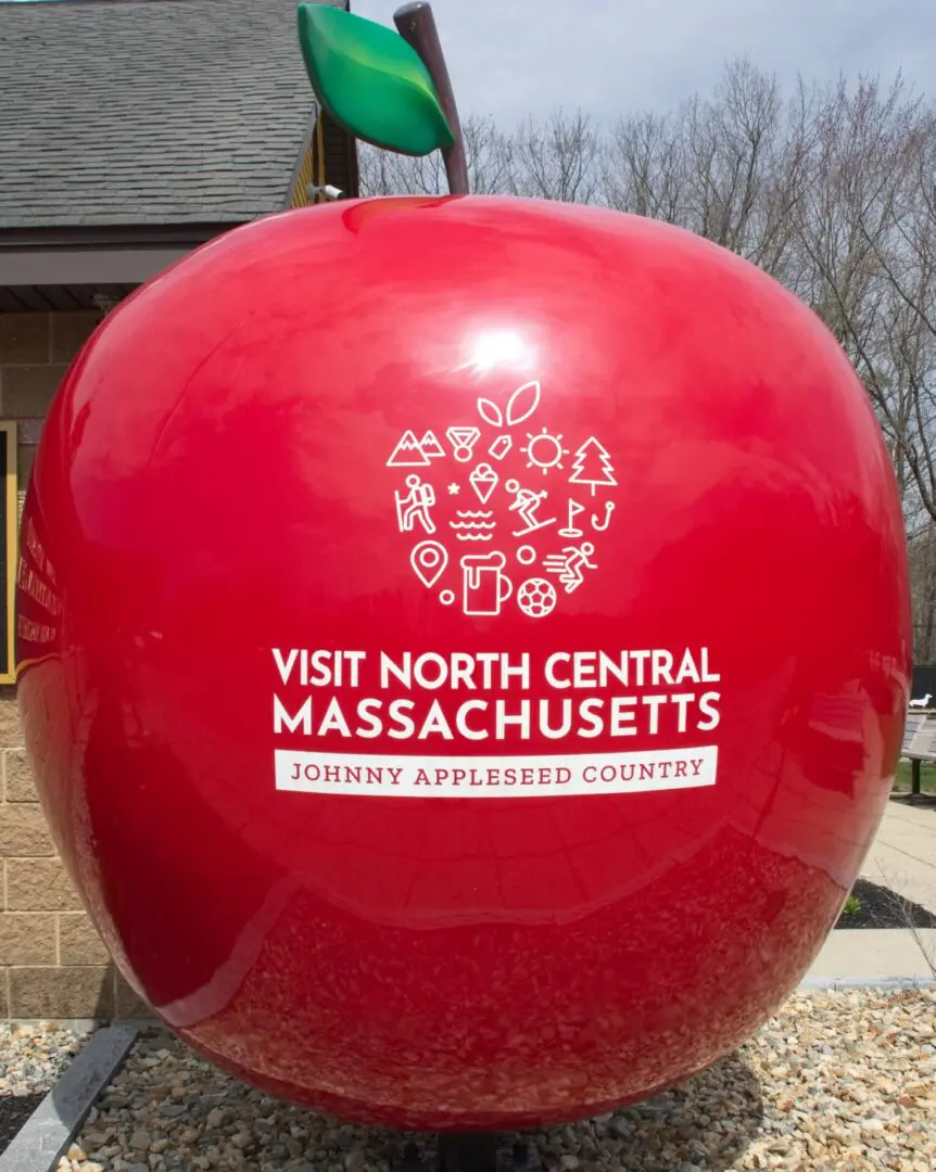 A large red apple with the words " visit north central massachusetts " on it.