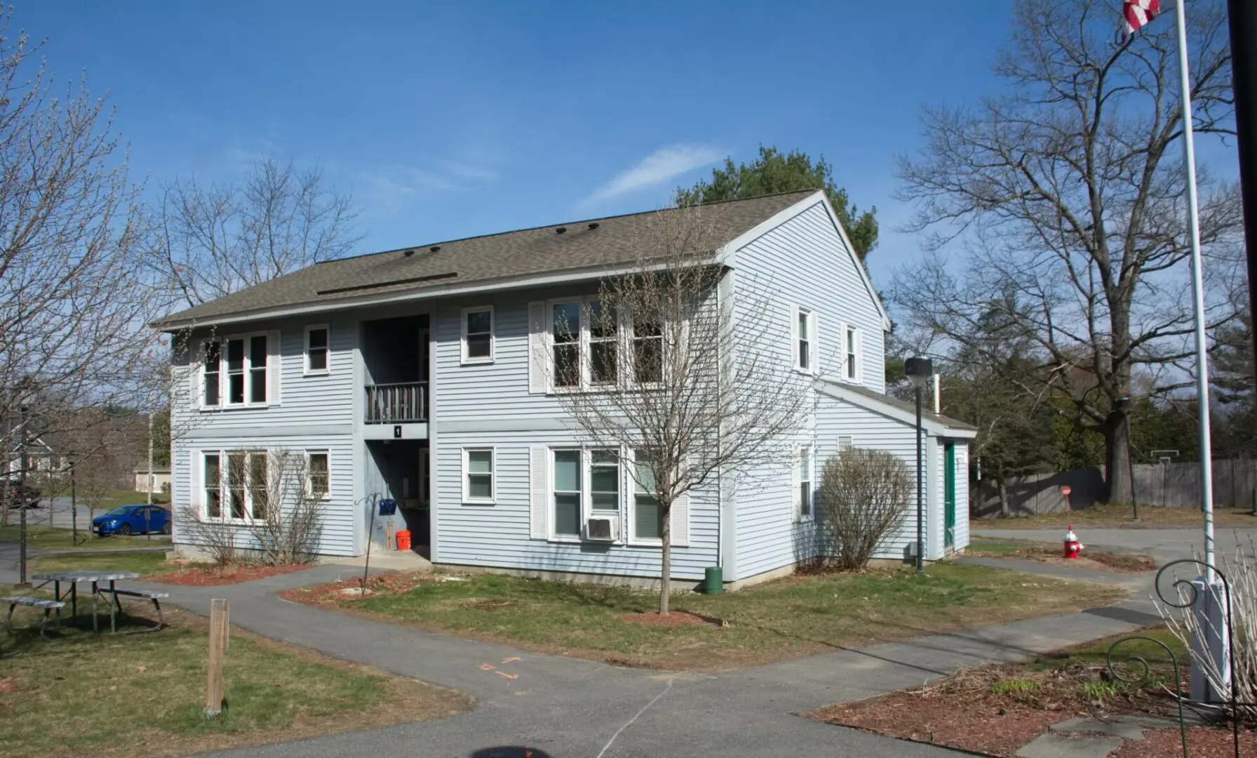 A white two story house with trees in front of it.