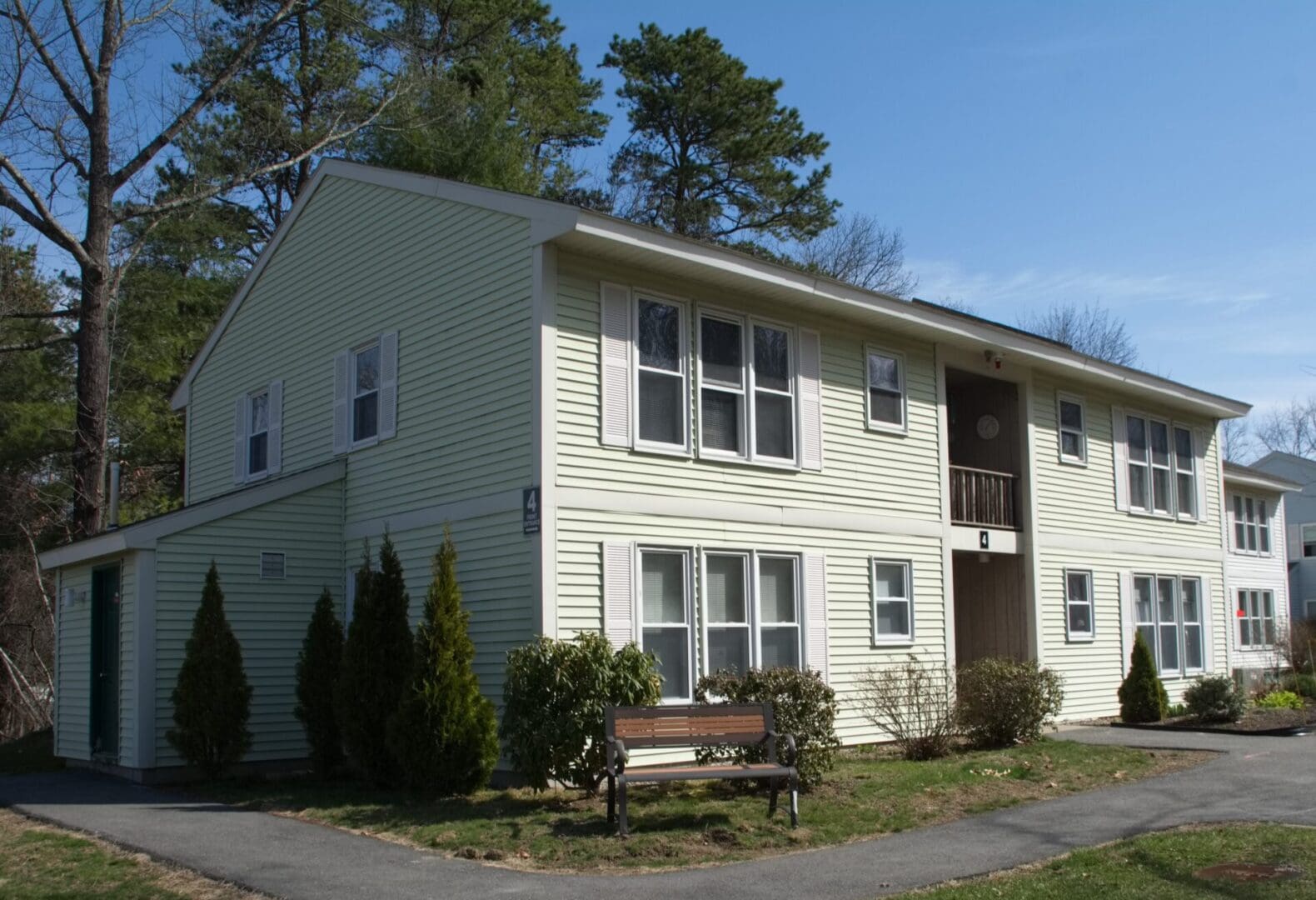 A white building with a bench in front of it.